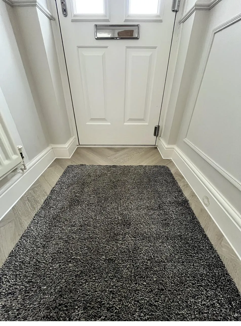 Skirting board sealed neatly against herringbone flooring by the front door