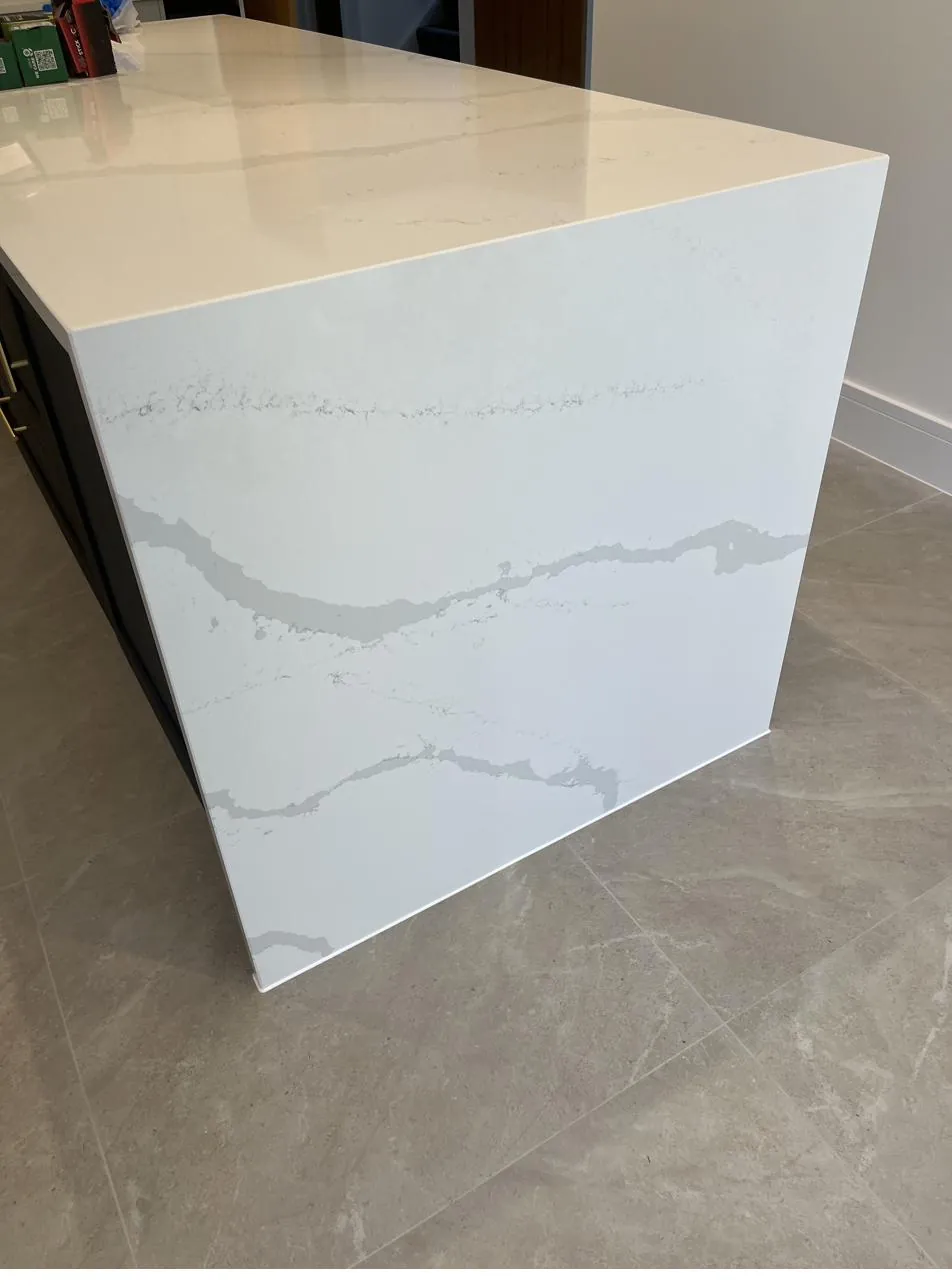 Quartz kitchen island edge sealed against tiled floor