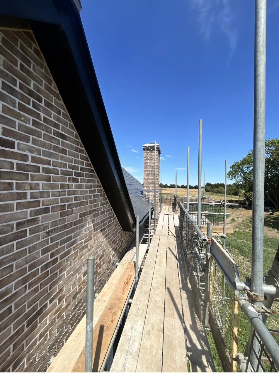 Roofline and brickwork sealant on a scaffolded new-build property