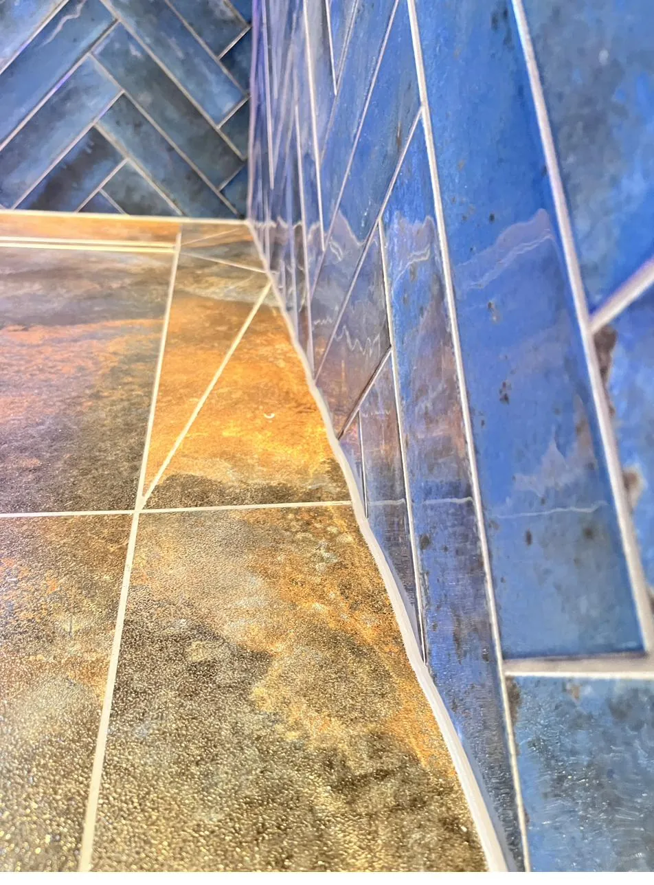 Close-up of sealant line on herringbone shower tiles